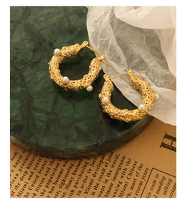 Detail of vintage gold U-shaped earrings with hammered texture, pearls and crystals