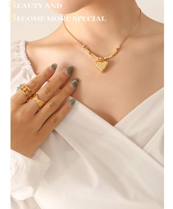 Dettaglio di una collana a serpente dorata con ciondolo a cuore e anelli coordinati