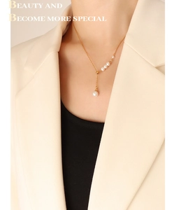 Elegant gold pearl Y-shaped necklace worn by a model in a beige suit jacket