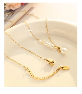 Detailed macro view of a gold pearl pendant necklace with K18 engraved tag on a ceramic plate