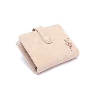 Close-up of leaf embroidery and round gold buckle on a beige PU leather wallet