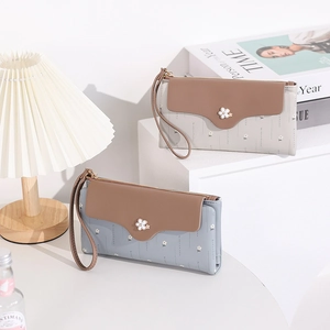 Detail of elegant long bifold wallets featuring floral metal accent and wristlet straps