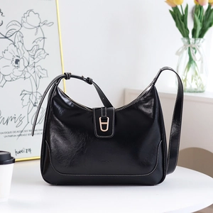 Détail d'un sac hobo en cuir noir avec surpiqûres blanches et boucle en métal doré