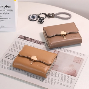Detail of short tri-fold wallets featuring golden cloud clasp and pearl charm pendant