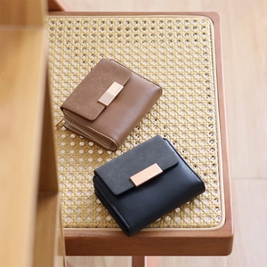 Detail view of brown and black PU leather wallets with elegant metal buckles on wooden chair