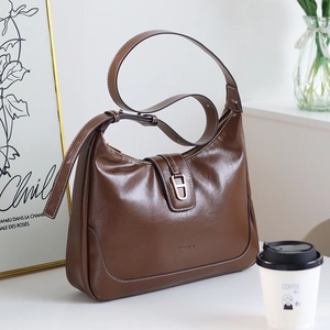 Détail du sac hobo en cuir marron foncé avec boucle dorée en H et finition lisse