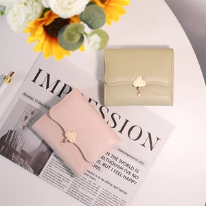 Close-up of pink and beige women's tri-fold wallets with floral clover charms and soft pearls