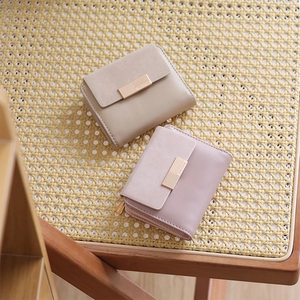 Detail of compact women's wallets in beige and pink leather with gold metal clasps