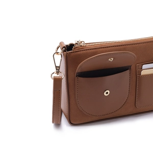 Dettaglio della borsa in pelle marrone con cerniera dorata e tasca frontale a scatto