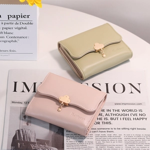 Detail of short tri-fold wallets in pastel green and pink with golden cloud charm