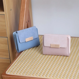 Detail of short PU leather wallets in blue and pink with metal buckle on rattan chair