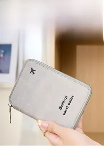 Close-up of grey leather travel wallet with zipper and airplane logo held by hand