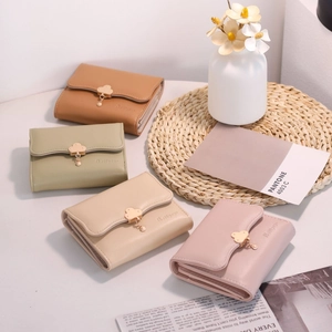 Close-up of assorted faux leather wallets with golden cloud buckles and floral pendants