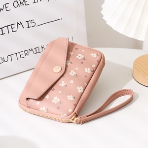 Detail of pink floral passport bag featuring a zipper closure and wrist strap