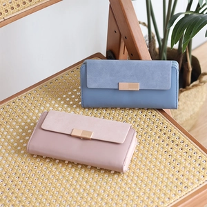 Détail de portefeuilles longs rose et bleu montrant la texture mate et les fermoirs en métal