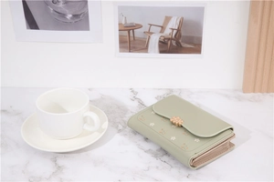 Detail of light green PU leather wallet with floral embroidery and golden flower clasp