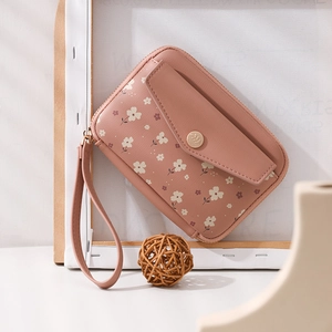 Detailed view of pink floral passport clutch with wrist strap and gold button closure