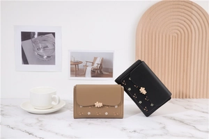 Detail of khaki and black PU leather wallets with floral prints and metal flower clasp