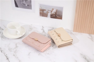 Close-up of floral print wallets in light pink and beige colors with gold flower clasp