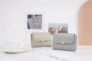 Detail of floral trifold wallets with metallic flower clasp in pastel green and blue colors