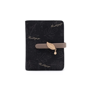 Close-up of black textured leather wallet featuring leaf prints and gold leaf charm detail