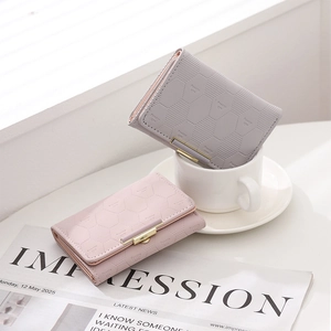 Detail of bifold wallets with hexagonal embossing, pretty eye text and gold metal clasp