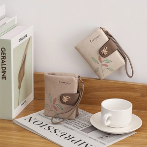Short PU leather leaf pattern wallet with bird buckle on a rustic bookshelf setup