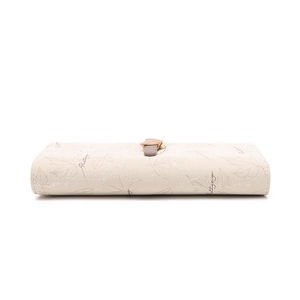 Close-up of beige long wallet featuring leaf print and golden metal clasp detail
