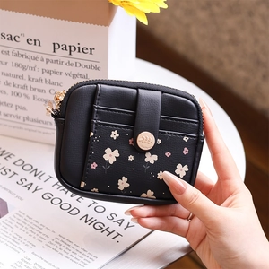 Detail of a compact black leather wallet featuring floral print and metal snap button