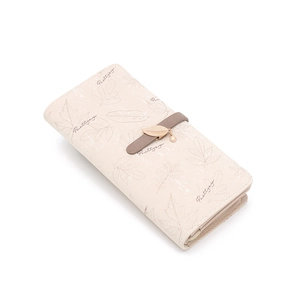 Detailed view of the creamy white long wallet with leaf print and golden leaf charm