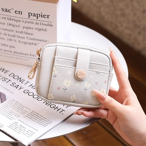 Close-up of a floral faux leather mini wallet with gold zipper and snap button