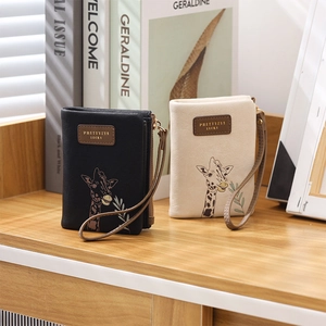 Detail of PU leather wallets in black and beige with giraffe prints and wrist straps
