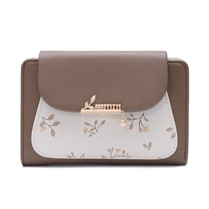Detailed view of women's bi-fold wallet featuring pebble leather and metal leaf pendant