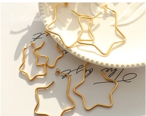 Three pairs of polished gold star hoop earrings in varying sizes on a white ceramic plate