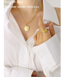 Détail du collier pendentif reine dorée et bague ondulée sur mannequin en chemise