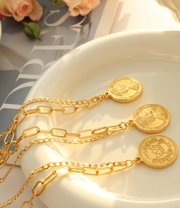 Détail de trois colliers de pièces d'or avec portrait d'Elizabeth II sur une assiette en céramique