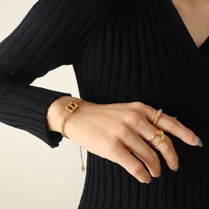 Cuban chain bracelet with letter B pendant and stackable gold rings on a model