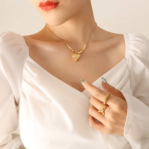 Collana a catena serpente con pendente a cuore dorato e anello in oro su una modella