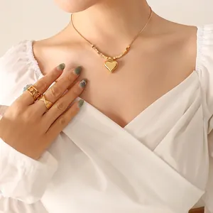 Collana con pendente a cuore dorato, catena a serpente e anelli su modella reale
