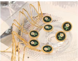 Detail of gold enamel necklaces with white flowers in a decorative glass bowl