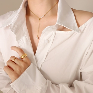 Elegant gold pearl necklace and ring set worn by model in a white shirt