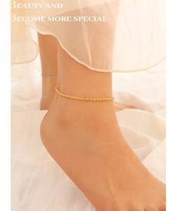 Close-up of elegant gold ankle bracelet on model with sparkling sand finish texture