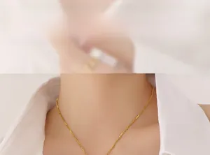 Detailed view of a gold bamboo-style chain necklace on model with polished finish