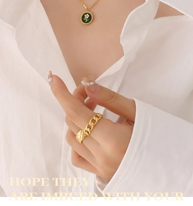 Detail of gold chain ring and black enamel daisy pendant necklace on a model