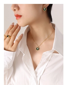 Macro detail of gold flower jewelry set featuring green enamel and white floral motif