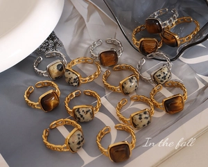 Detail of vintage square tiger eye and dalmatian jasper rings with gold chain texture