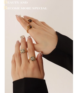 Detail of four golden chain rings set with tiger eye and marble stones on model fingers