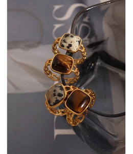 Macro shot of vintage gold chain rings with square tiger eye and dalmatian stone insets