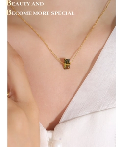 Détail d'une fine chaîne dorée avec pendentif en cristal vert émeraude sur un mannequin