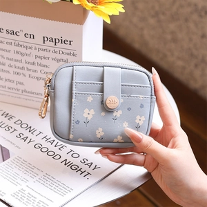 Close-up of light blue floral wallet with snap card slot and gold ring zipper detail